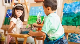 Group of kids working on a painting of a landscape during art class at school