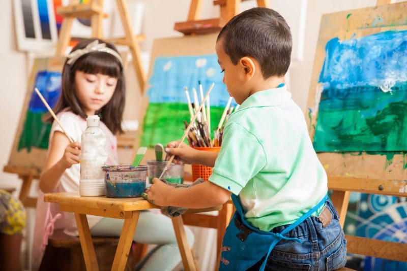 Group of kids working on a painting of a landscape during art class at school