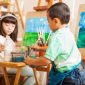 Group of kids working on a painting of a landscape during art class at school